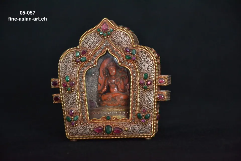 Bogenförmige Filigran-Amulettbox mit roten und grünen Steinen, rote Tara-Figur im Fenster