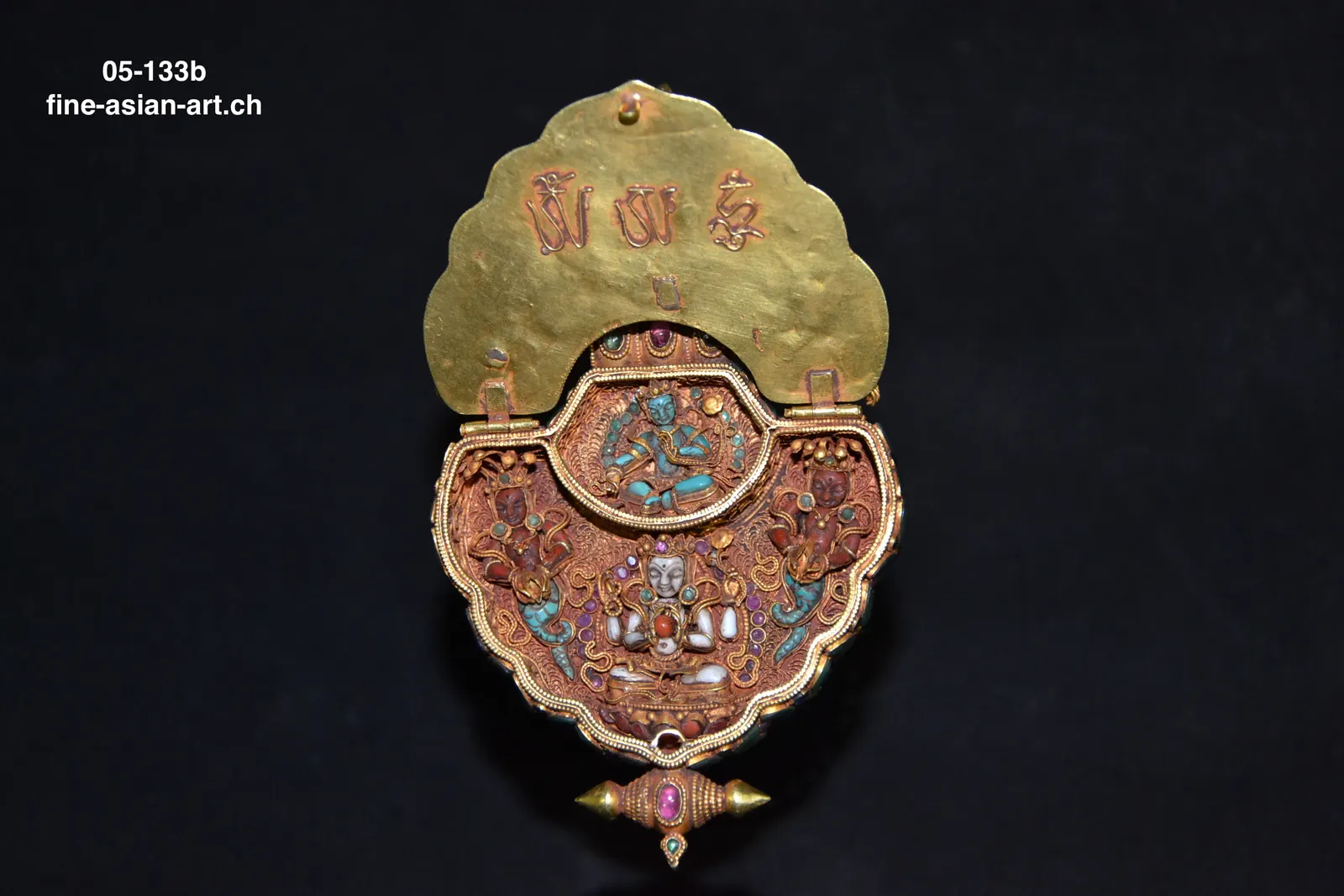 Geöffnete goldene Amulettbox mit graviertem Deckel, rotem Innenraum, kleiner Figur und Anhänger