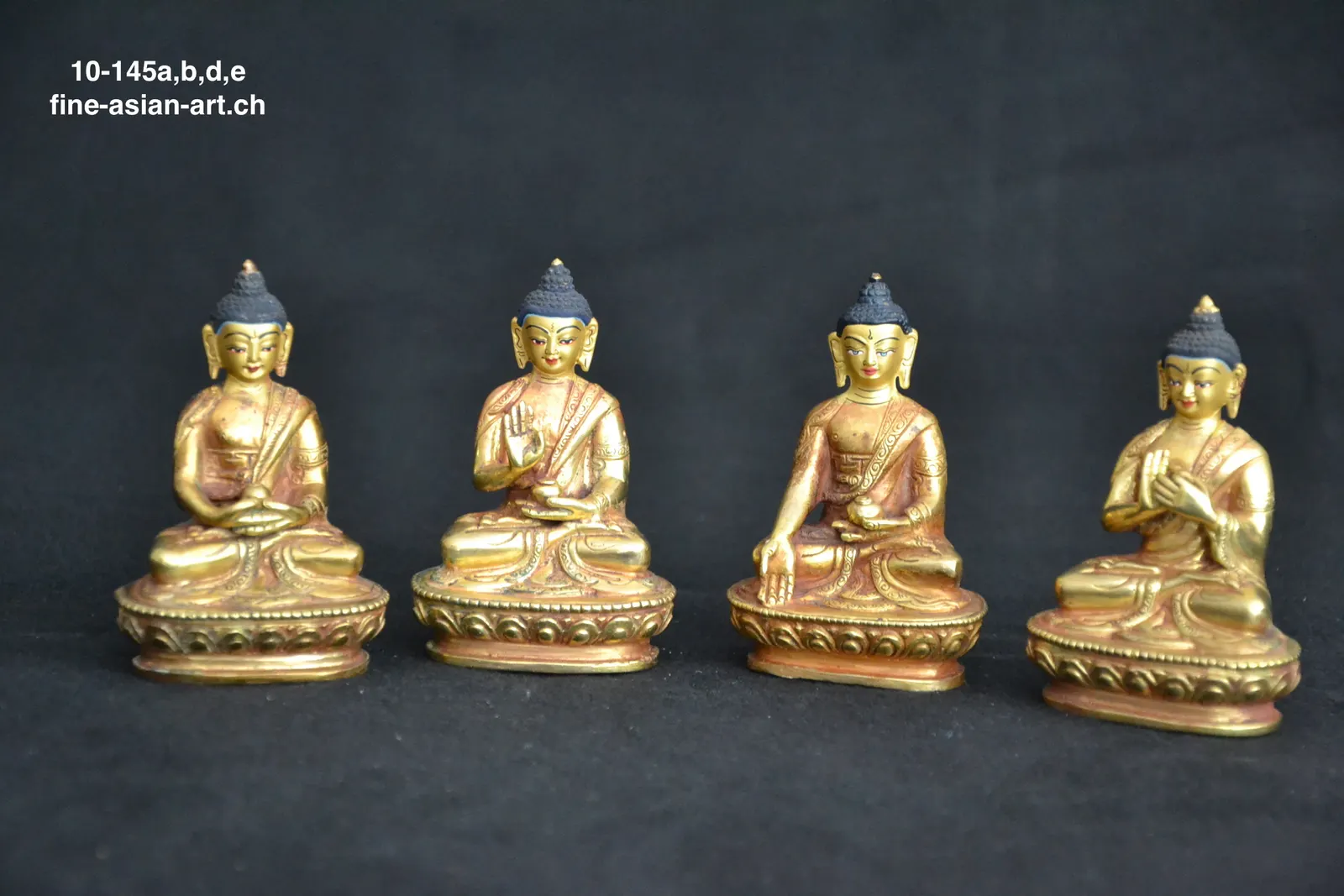 Vier kleine goldfarbene Buddha-Figuren in einer Reihe auf Lotossockeln mit verschiedenen Handgesten