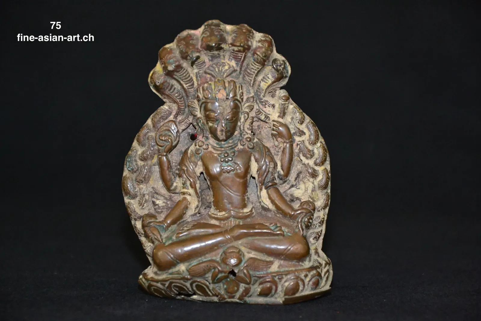 Kleines dunkles Metallrelief einer sitzenden Gottheit unter mehrköpfiger Schlangenhaube und Flammenaureole